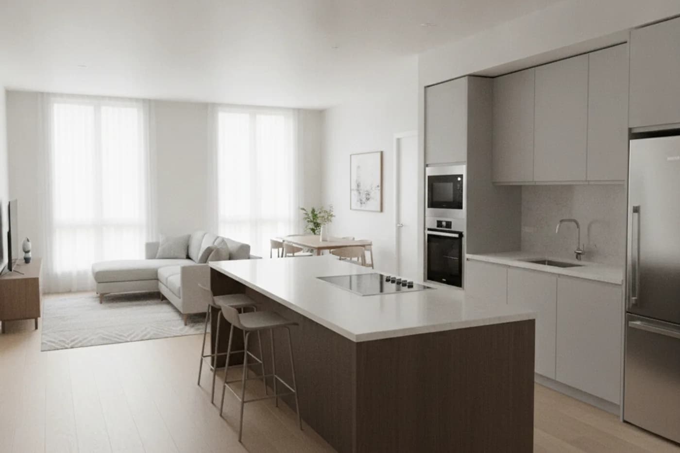 An open kitchen with a long island holding a cooktop and two bar stools, a wall of gray cabinets with built-in ovens, a sink and a refrigerator, and a living area beyond